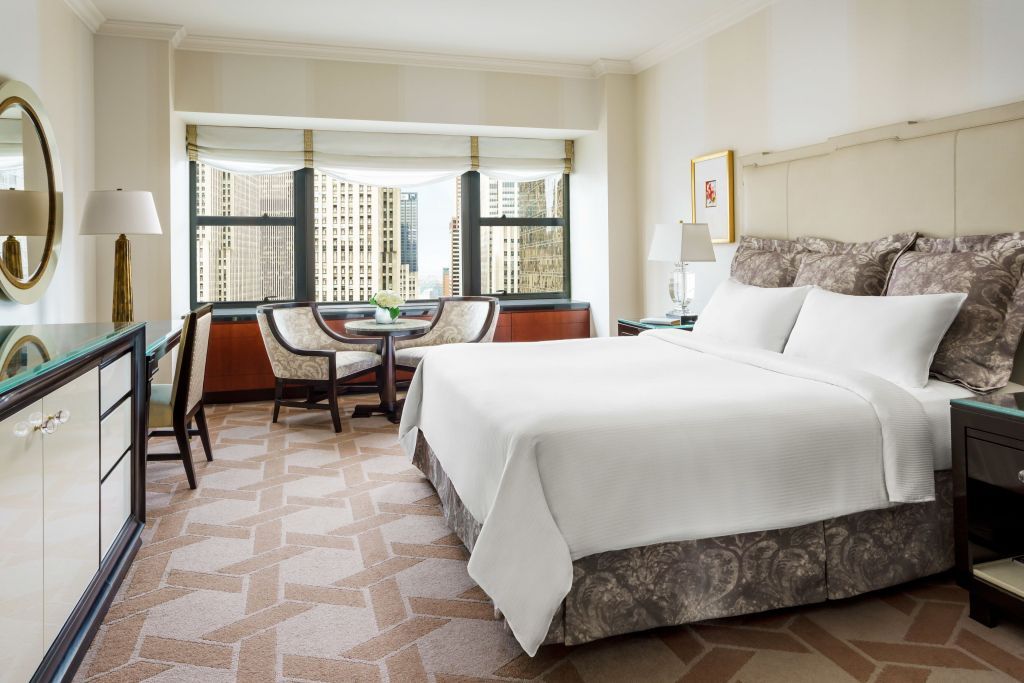 Geräumiges Zimmer mit Doppelbett und Aussicht auf die Skyline durch große Fenster