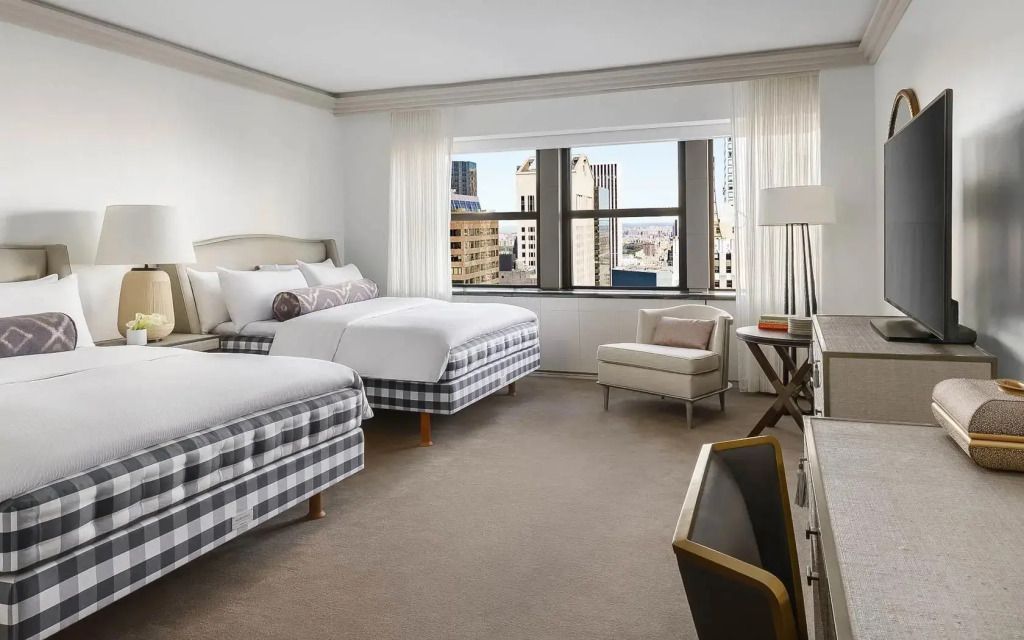 Skyview Suite Schlafzimmer mit zwei Doppelbetten und Stadtblick Fenster.