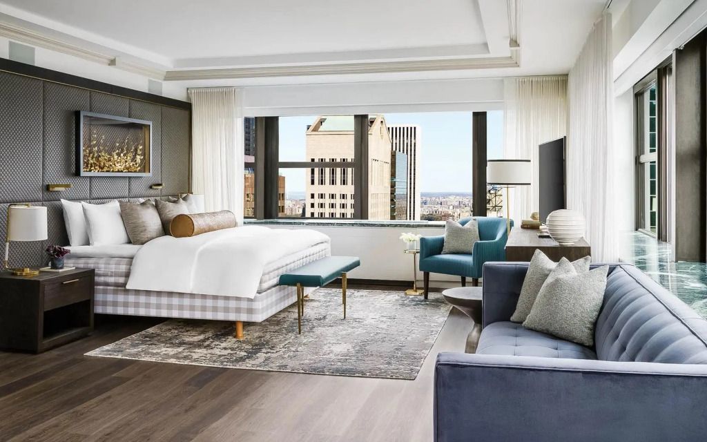 Skyview Suite mit Kingsize-Bett, gemütlichen Sesseln und Fenster mit Stadtblick.