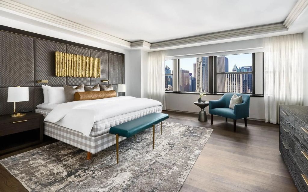 Helles Schlafzimmer der Suite mit großem Fenster und Stadtblick