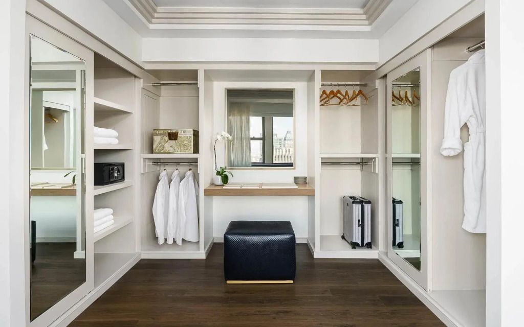 Geräumiger begehbarer Kleiderschrank mit Spiegel, Kofferablage und Holzoptik.