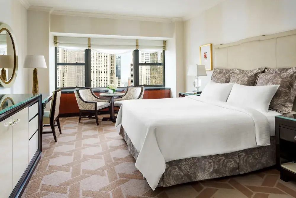 Helles Zimmer mit Doppelbett und Sitzbereich mit Aussicht auf die Skyline.