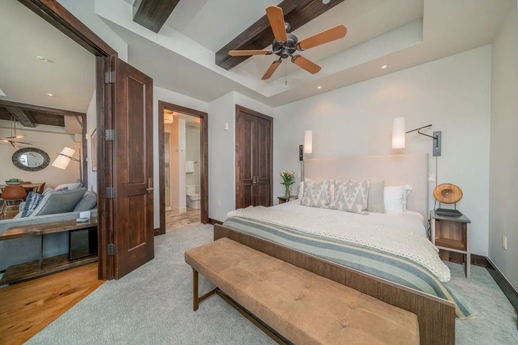 Modernes Schlafzimmer mit großem Bett, Holzdetails und Zugang zu einem Badezimmer.