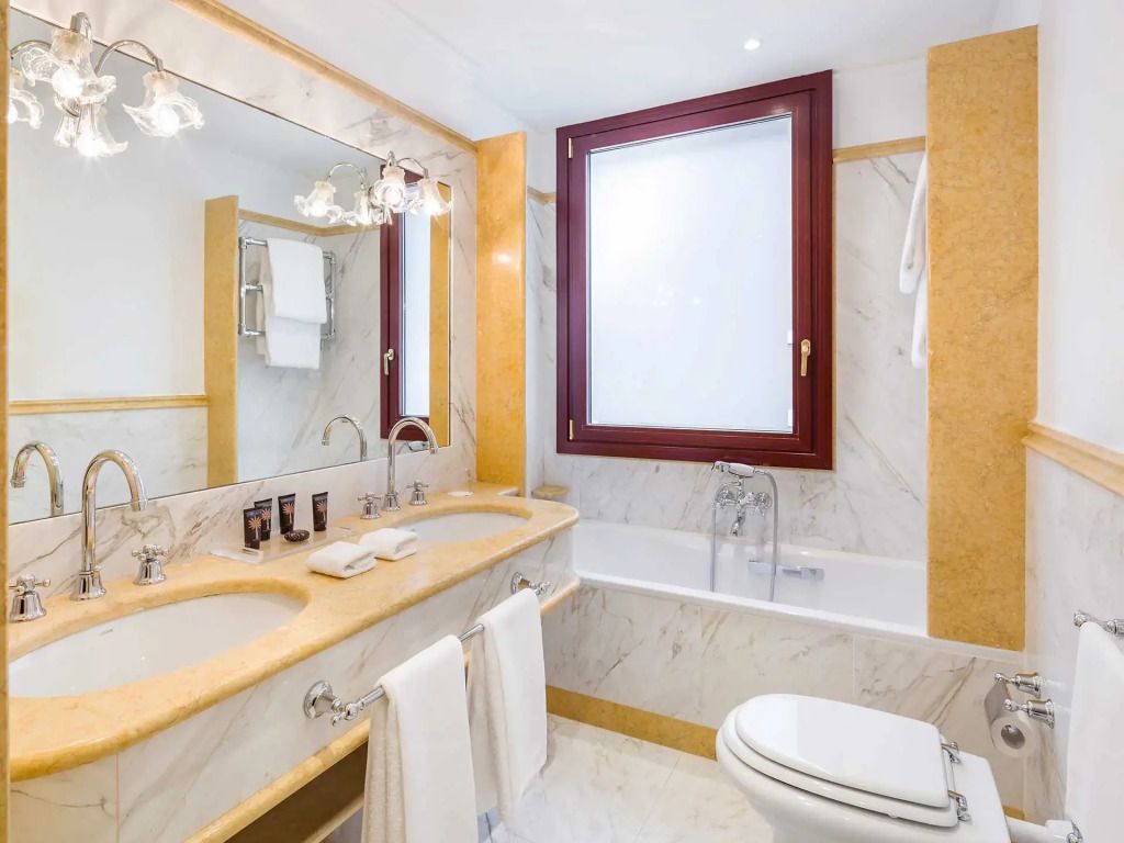 Helles Badezimmer mit Marmorakzenten, großer Spiegel. Raffiniertes Design.