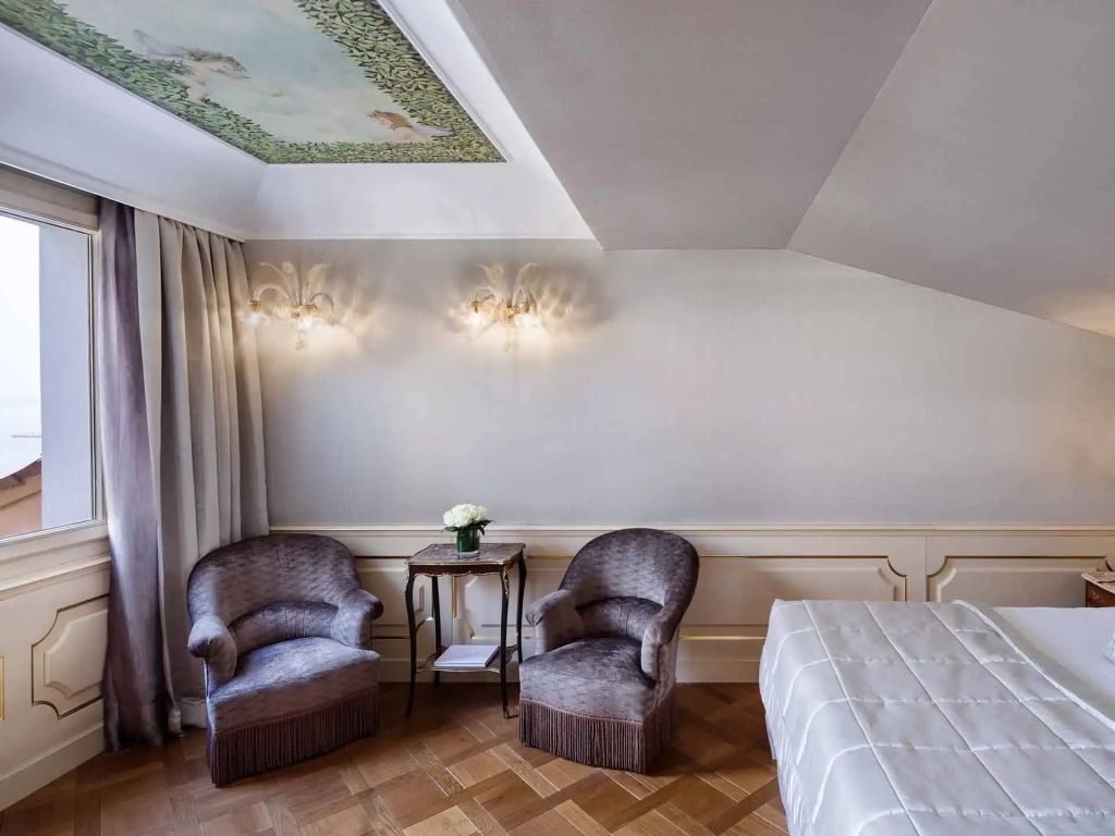 Sitzecke in der Suite mit weichen Sesseln, dezenter Wandbeleuchtung und floralen Details