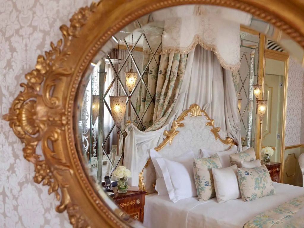 Prunkvolles Bett in der San Giorgio Terrasse Suite mit geschwungenem Spiegelrahmen.