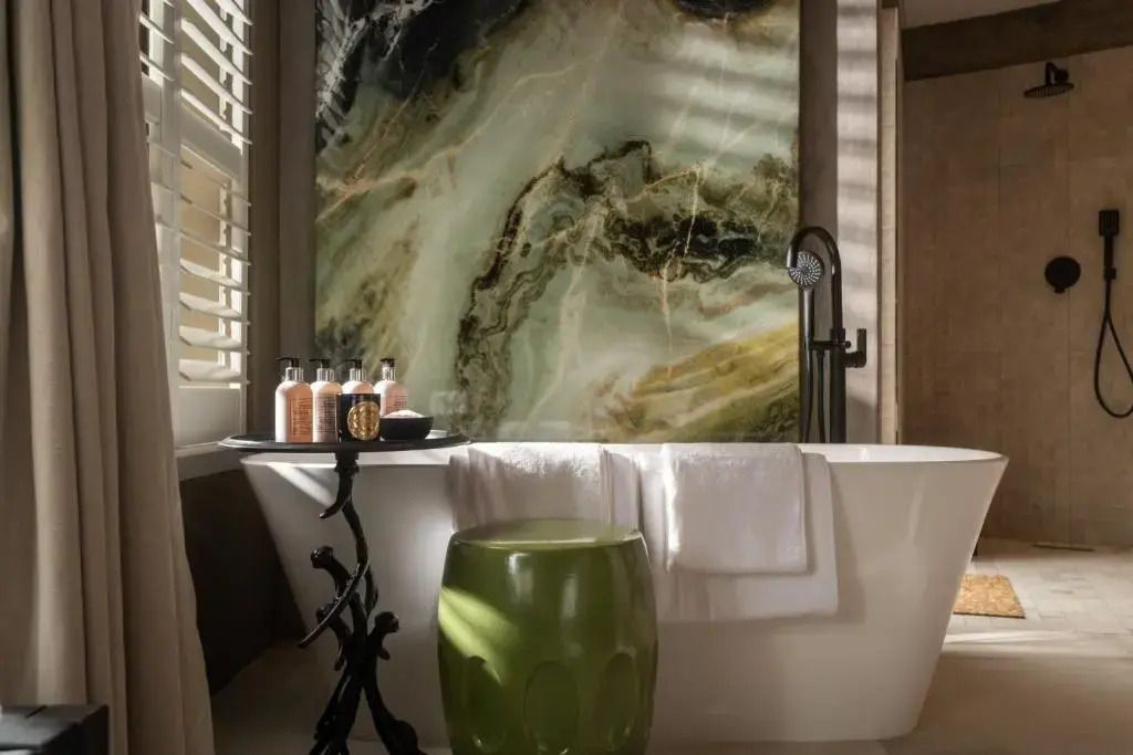 Luxuriöses Badezimmer mit großer Badewanne und Marmorwand samt Tageslicht durch Fenster