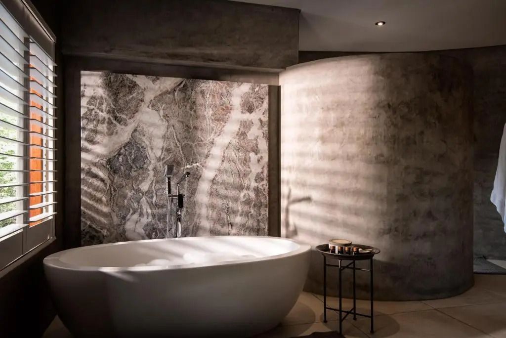 Elegantes Badezimmer mit freistehender Badewanne und edler Steinwand