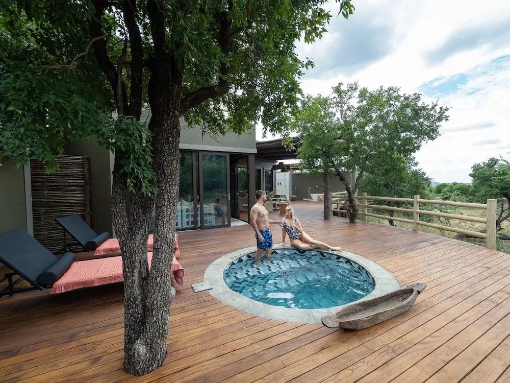 Terrasse mit Whirlpool und Sitzbereich im Freien unter Bäumen