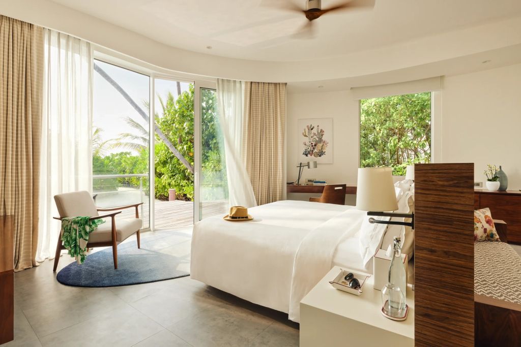 Helles Schlafzimmer mit Doppelbett und Blick auf tropische Terrasse