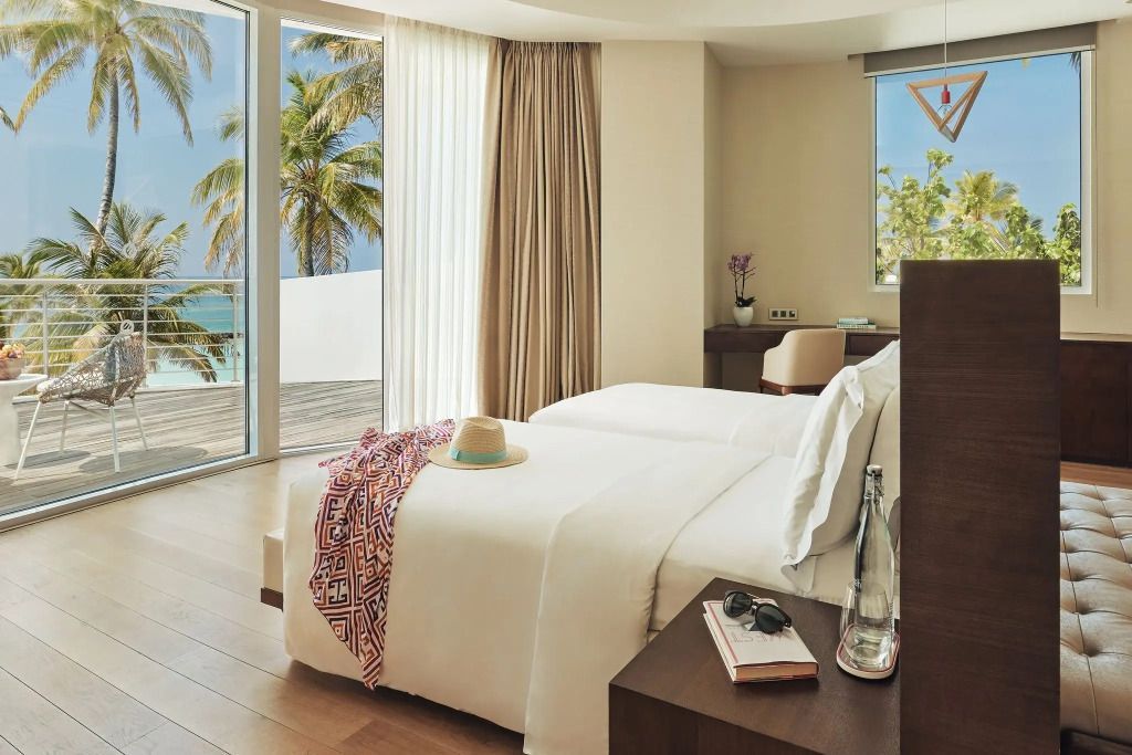 Gemütliches Schlafzimmer mit zwei Betten, Panoramablick auf den Strand und Palmen