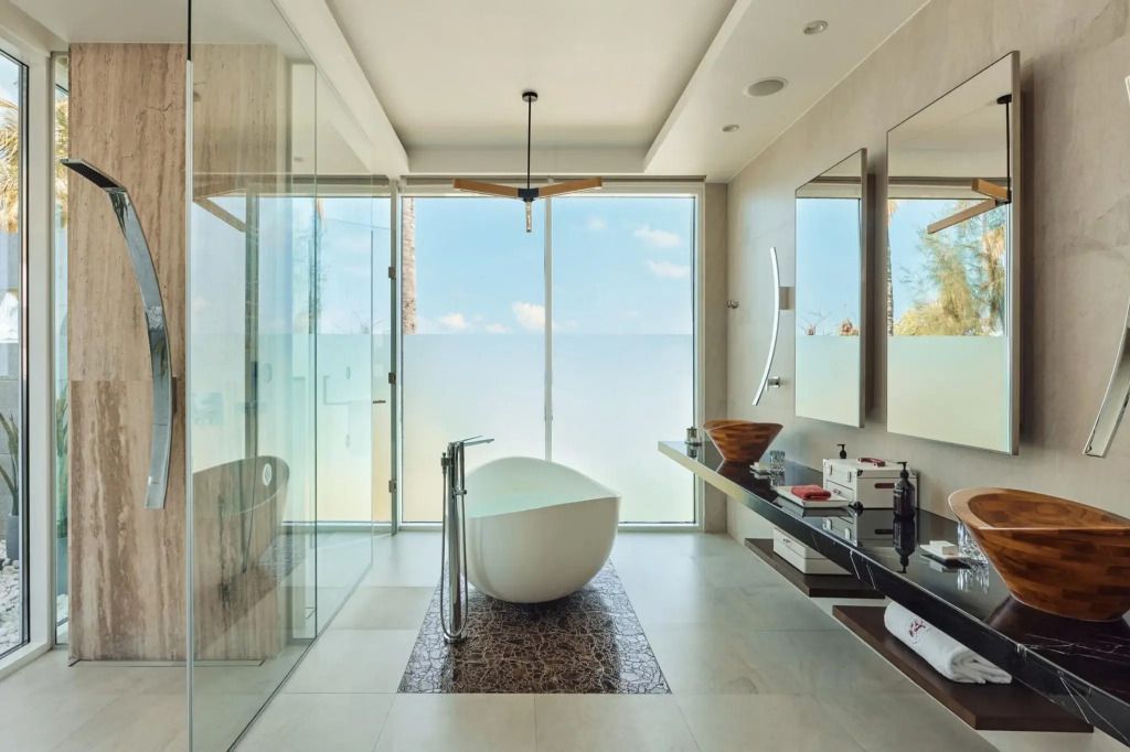 Elegantes Badezimmer mit Badewanne und Meerblick durch Glasfront