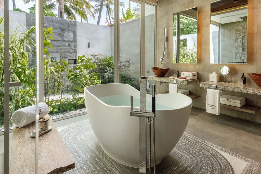 Luxuriöses Badezimmer mit freistehender Badewanne und Gartenblick