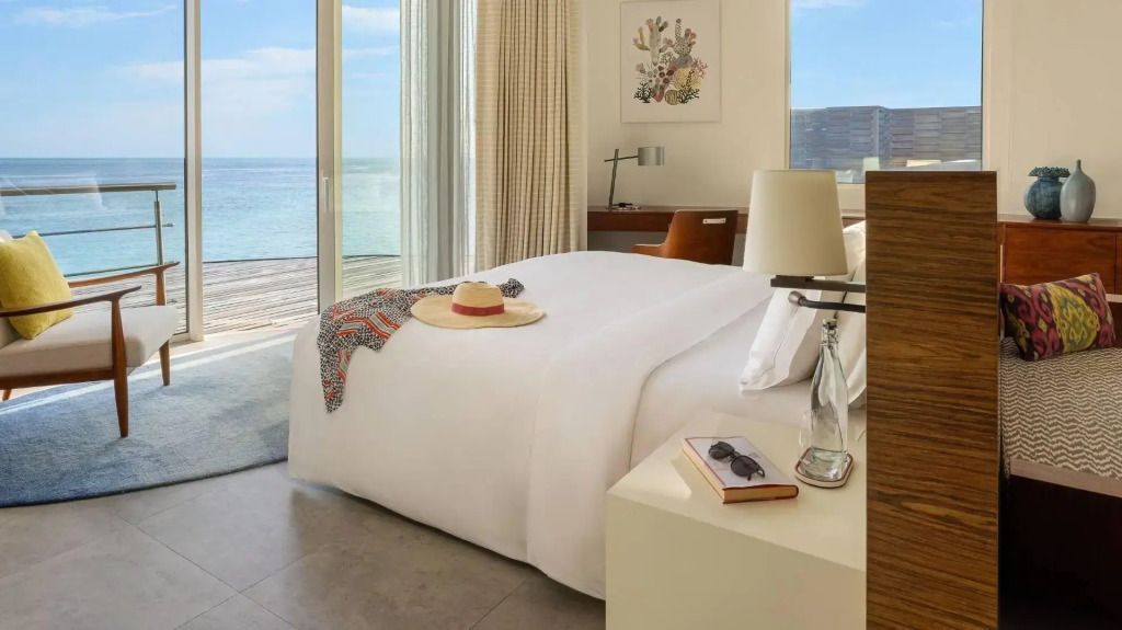 Helles Schlafzimmer mit Doppelbett und Meerblick durch große Fenster