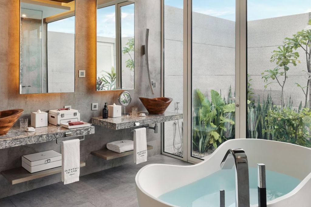 Badezimmer mit großer Badewanne, Doppelwaschbecken und Zugang zum Garten