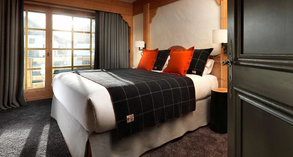 Gemütliches Doppelzimmer mit Holzelementen und dekorativen Kissen im Hotel Le M de Megève