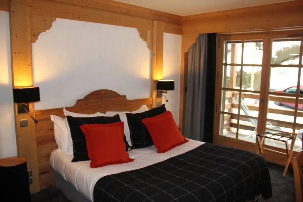 Komfortables Doppelbett im Hotelzimmer mit Holzverkleidung und roten Akzentkissen