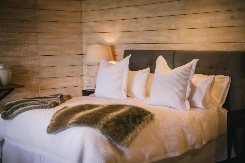 Gemütliches Schlafzimmer mit Doppelbett und rustikaler Holzwand