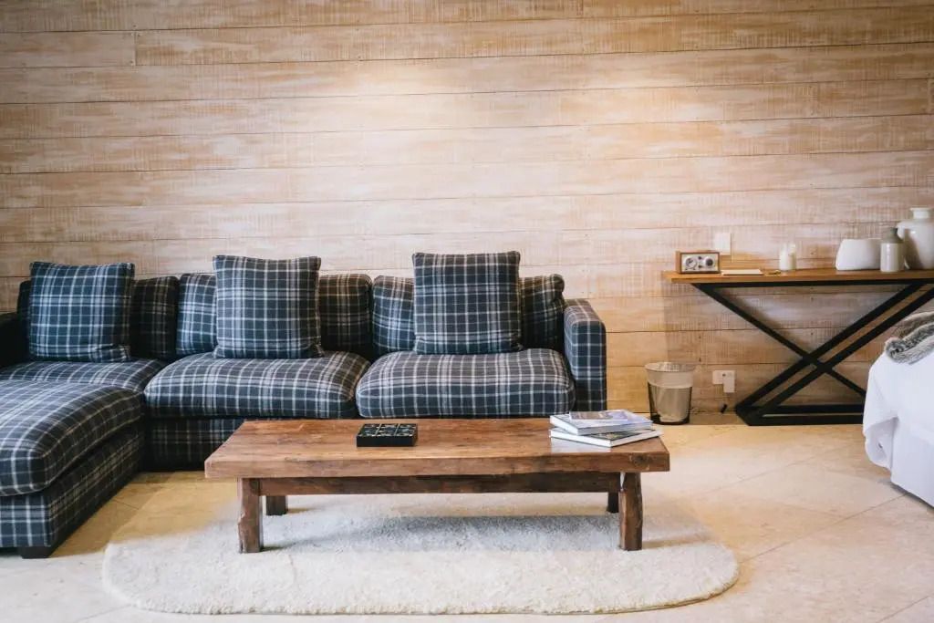 Wohnbereich mit karierter Couch und Holztisch in einer Suite