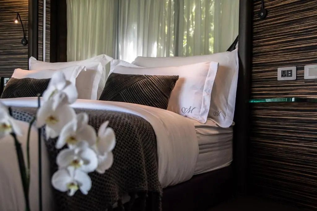 Detailaufnahme eines gemütlichen Bettes mit zarten Stoffen und weißen Orchideen