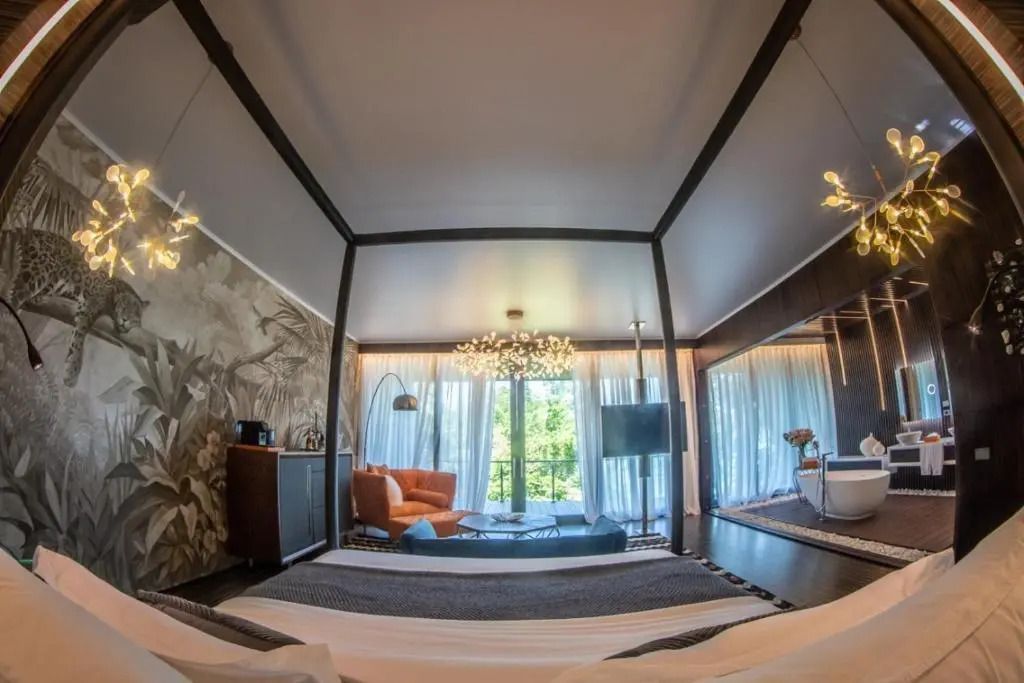 Zimmeransicht mit Himmelbett, Designerleuchten und raumhohen Fenstern