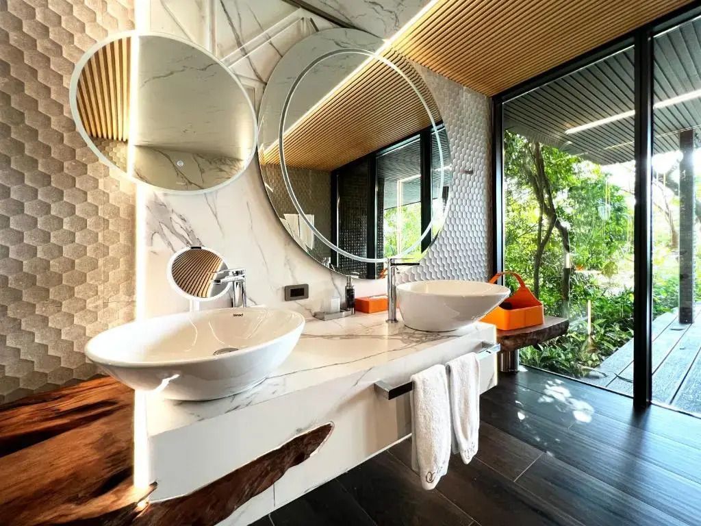 Luxuriöses Badezimmer mit Marmor, zwei Waschbecken und runden Spiegeln