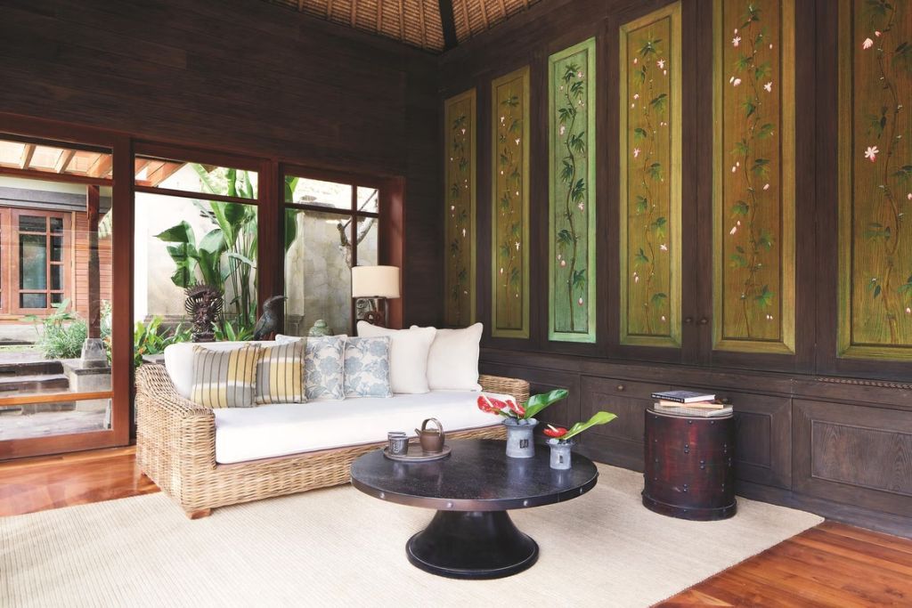 Gemütliches Sofa mit Kissen und kunstvollen grünen Paneelen in einer luxuriösen Villa