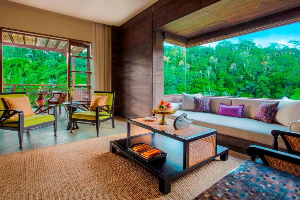 Wohnbereich einer Suite mit Sitzgelegenheit und Ausblick auf tropische Vegetation