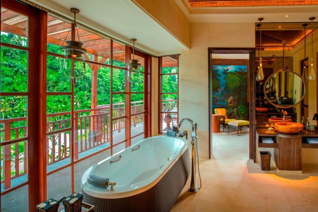 Badezimmer mit freistehender Badewanne und Ausblick auf üppiges Grün