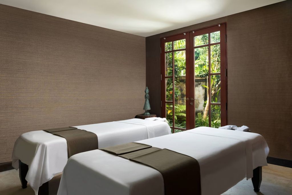 Entspannungsraum mit zwei Behandlungsliegen und Gartenblick im Mandapa Spa.