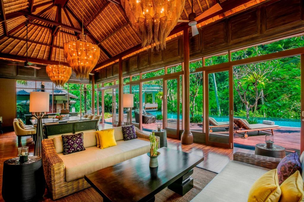 Luxuriöser Wohnbereich mit stilvollen Holzakzenten und Poolblick in der Mandapa Villa.