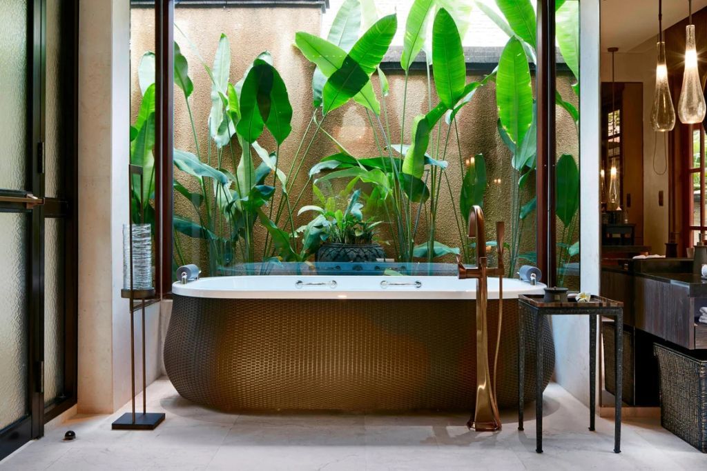 Luxuriöse Badewanne mit Goldakzenten und tropischen Pflanzen