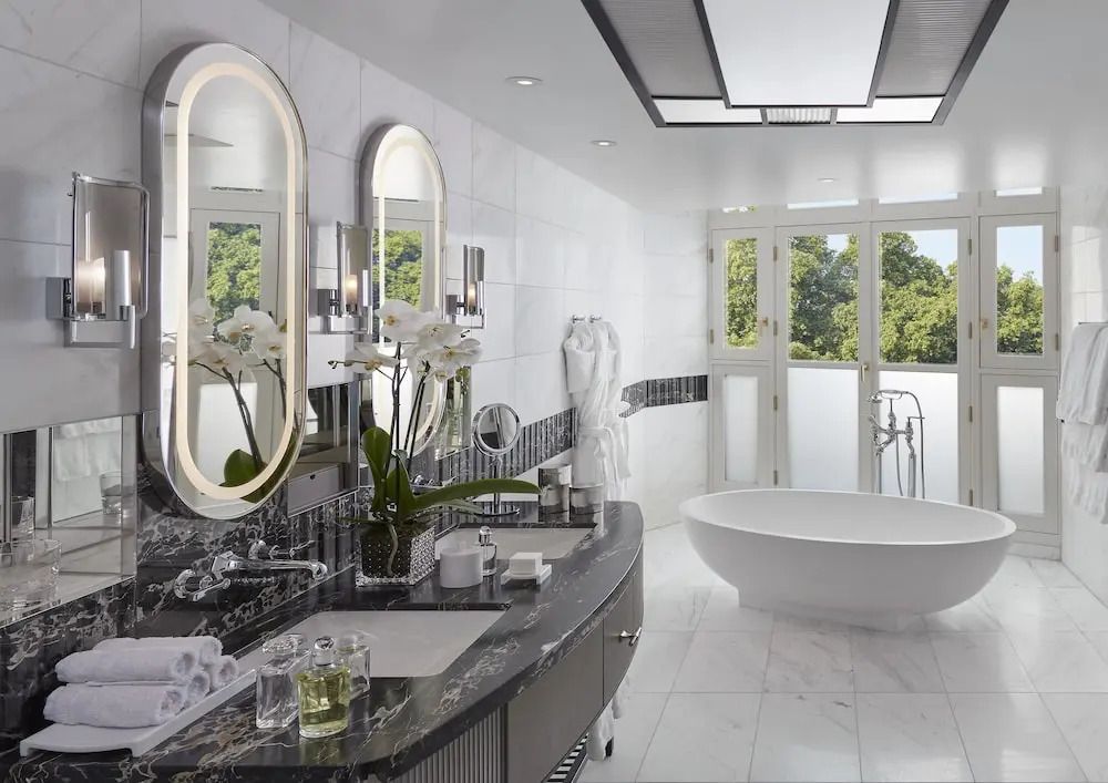 Luxuriöses Badezimmer mit freistehender Badewanne und großen Fenstern im Hyde Park Zimmer.