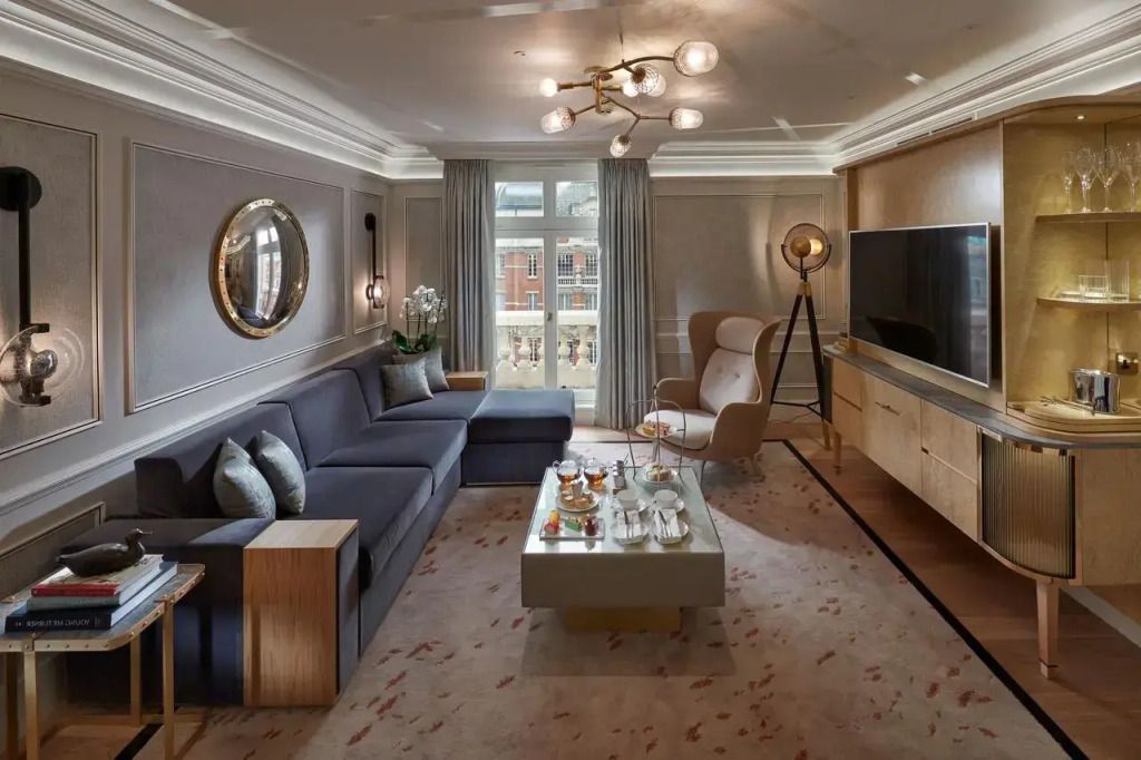 Elegantes Wohnzimmer der Knightsbridge Suite mit Sofa, Sessel, Tisch und großen Fenstern.