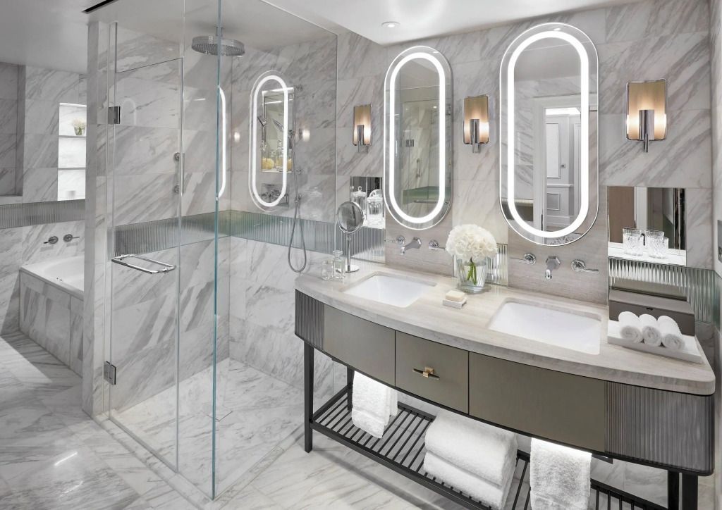 Modernes Badezimmer mit eleganten Marmordetails und großen Spiegeln.