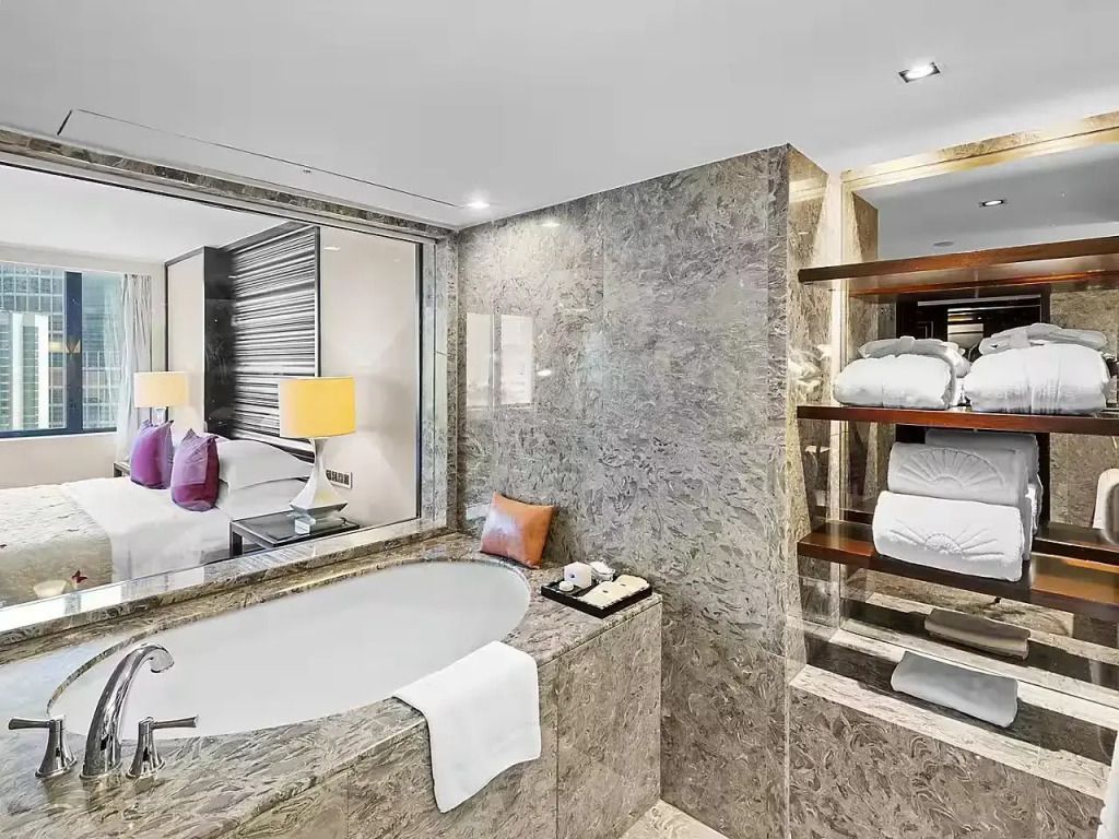 Modernes Badezimmer mit Marmordekor und Blick ins Hotelzimmer