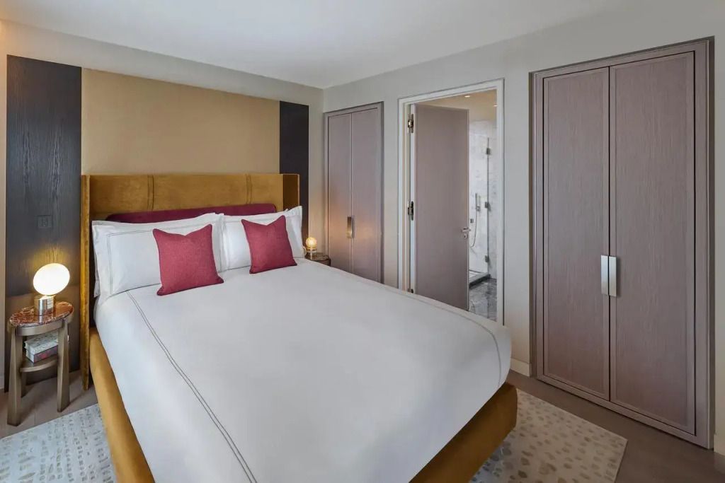 Elegantes Schlafzimmer mit Doppelbett und roten Kissen, verbunden mit luxuriösem Bad.