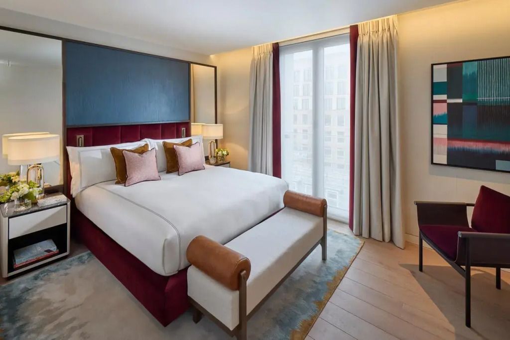 Helles Schlafzimmer mit großem Bett, gepolsterten Kopfteilen und modernen Möbeln.