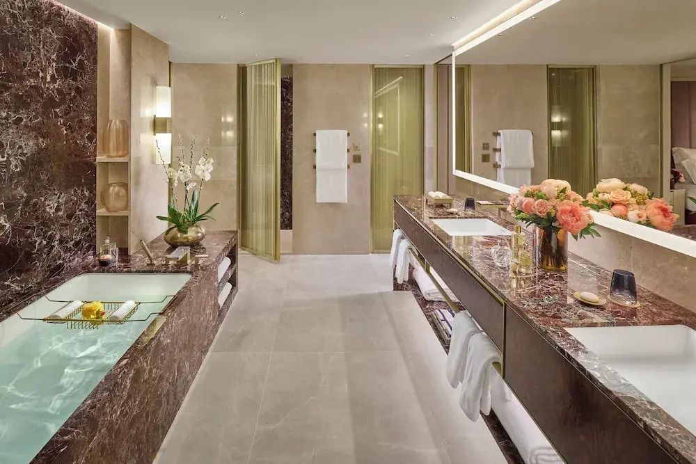 Großes Badezimmer mit Marmoroberflächen und eleganten goldenen Akzenten.