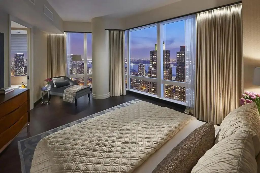 Helles Schlafzimmer mit Panoramablick auf die erleuchtete Stadtlandschaft