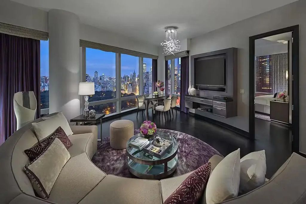 Luxuriöses Wohnzimmer mit großen Fenstern und Stadtpanorama bei Nacht
