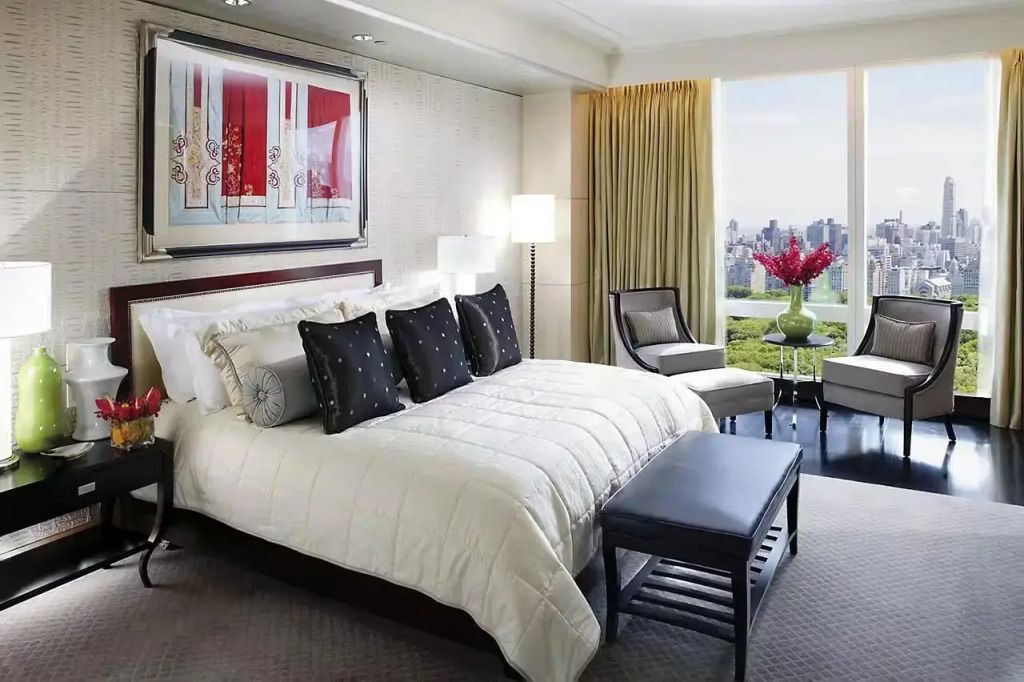 Elegante Schlafzimmer-Suite mit großem Fenster und Aussicht auf die Stadt.