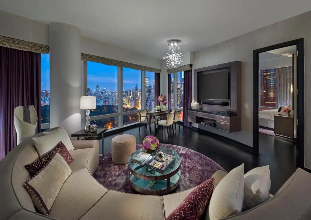 Großzügiges Wohnzimmer in der Suite mit Blick auf die Stadt bei Dämmerung