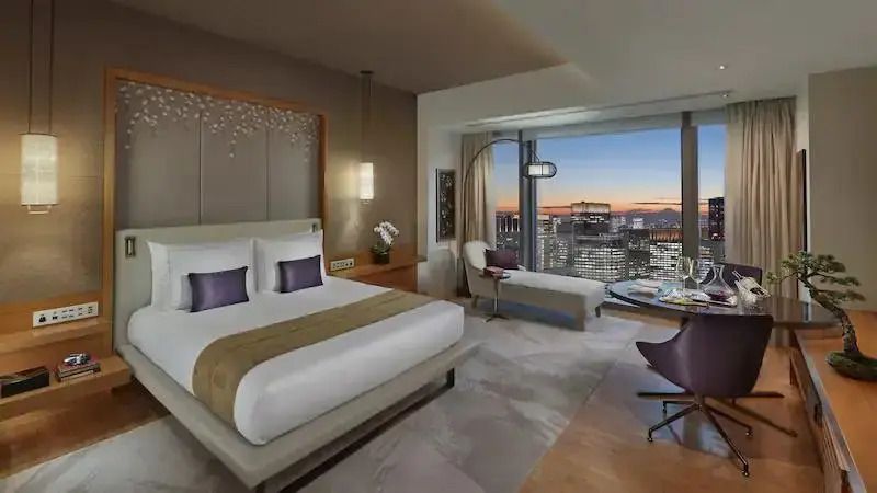 Geräumiges Hotelzimmer mit Kingsize-Bett und spektakulärer Aussicht auf die abendliche Skyline