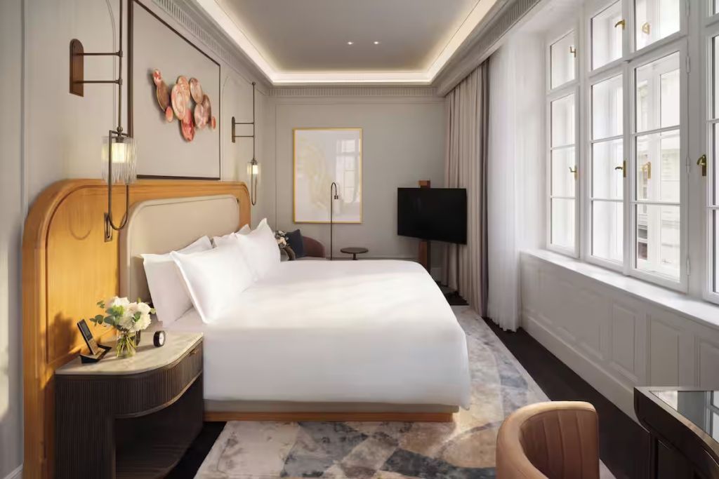 Elegantes Schlafzimmer mit Doppelbett, Kunst an der Wand und Fenster mit Tageslicht.