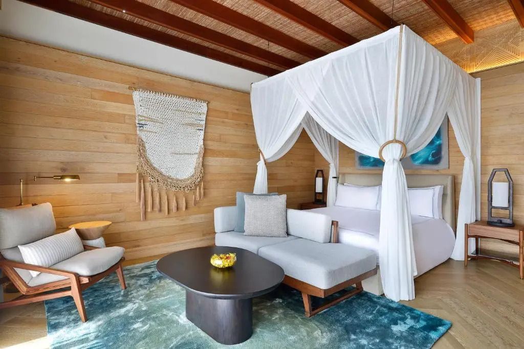 Luxussuite mit Himmelbett, Holzwänden und gemütlicher Sitzecke in warmen Tönen