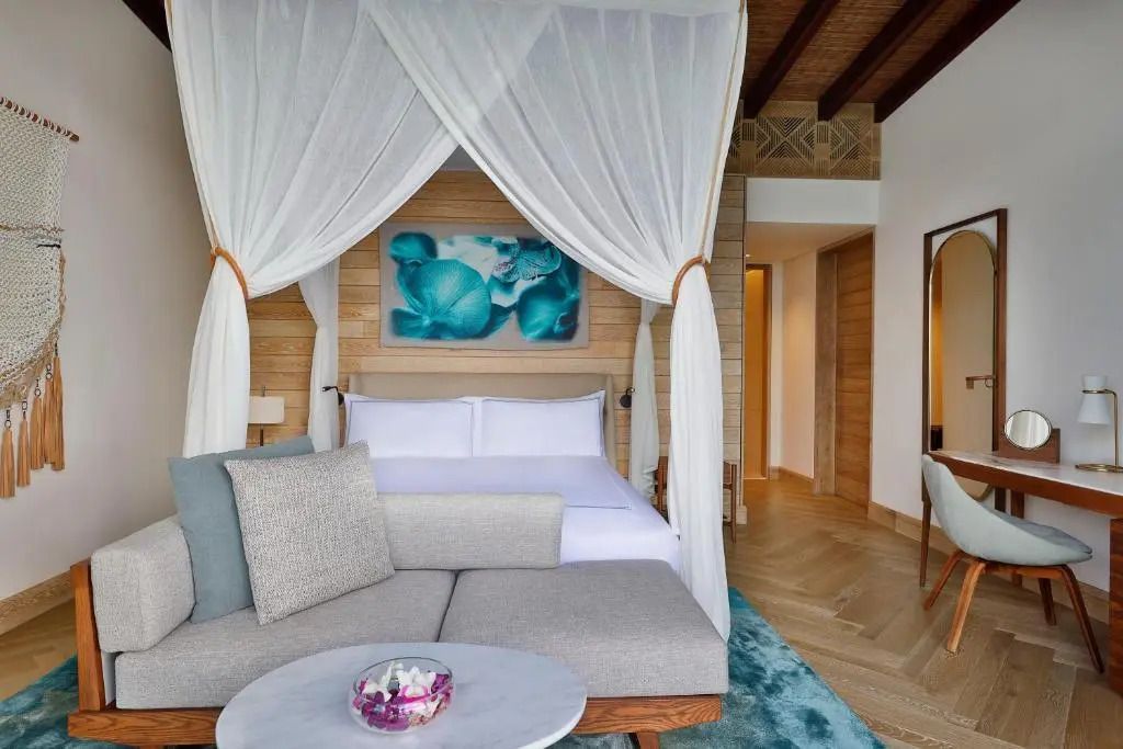 Luxusbett mit Baldachin in Suite, dekoriert mit Kunstwerk und bequemer Couch