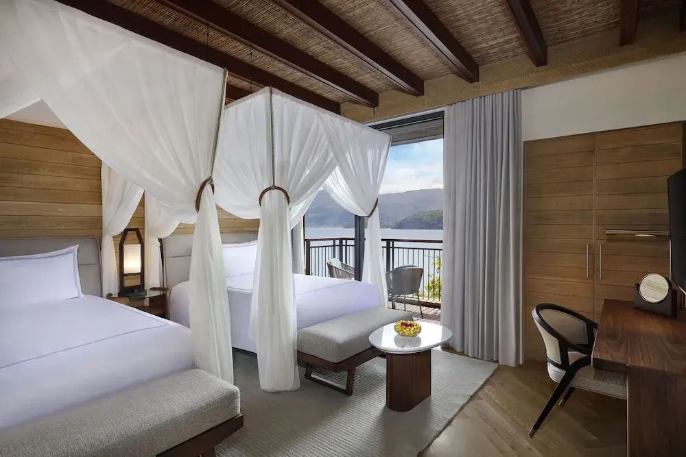Zwei Einzelbetten mit Baldachin in einem modernen Hotelzimmer mit Meerblick.