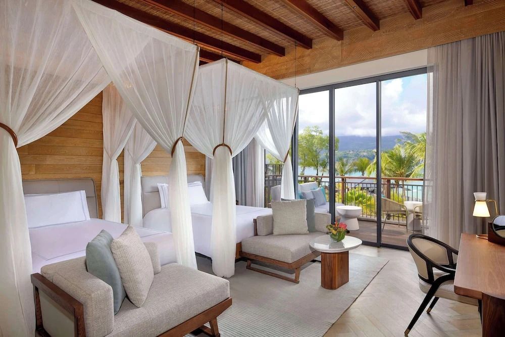 Luxuriöses Zimmer mit zwei Einzelbetten und Blick auf den tropischen Garten und das Meer.