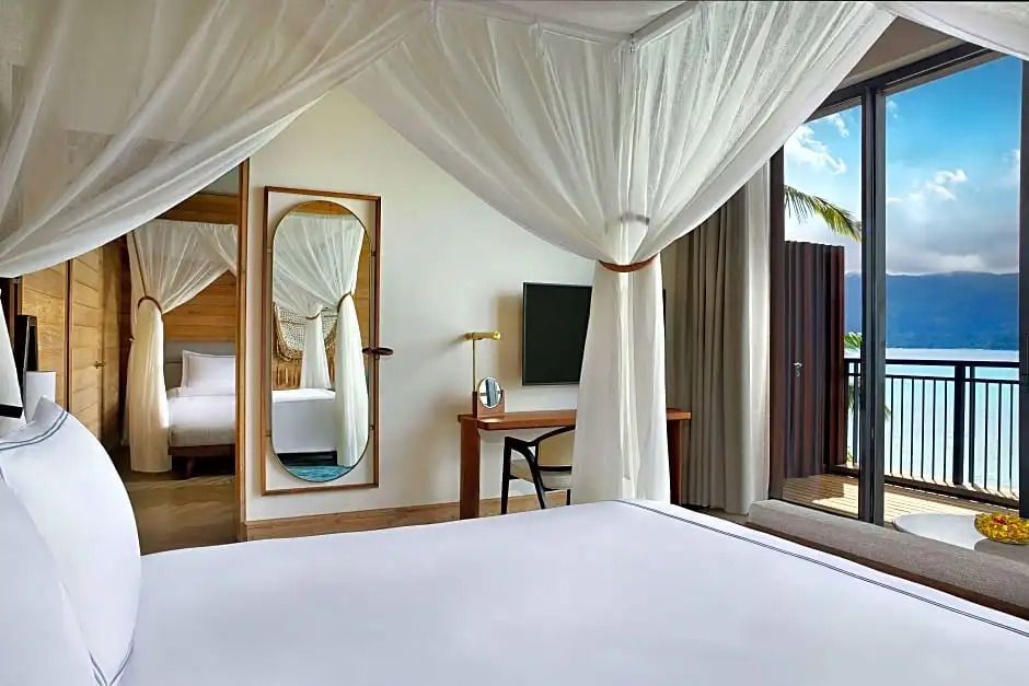 Schlafzimmer mit Himmelbett und Zugang zum Balkon mit Meerblick